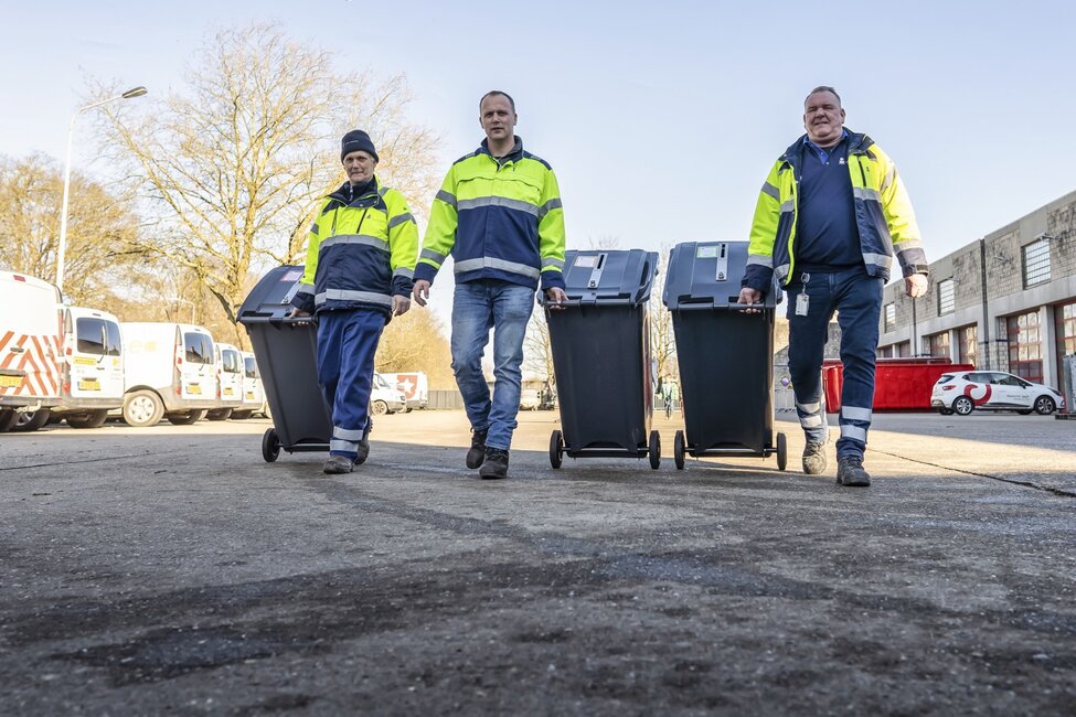 Mannen lopen met afvalcontainers